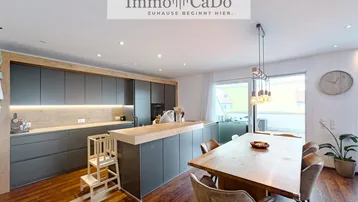 Moderne offene Küche mit Essbereich, Holzboden und Zugang zu einer Terrasse.