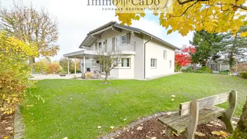 Großzügiger Gartenbereich mit Rasenfläche, Bäumen und einer Holzbank vor dem Einfamilienhaus.