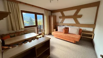 Gemütlicher Wohnbereich mit Sofa, Esstisch und Blick auf die umliegende Berglandschaft.