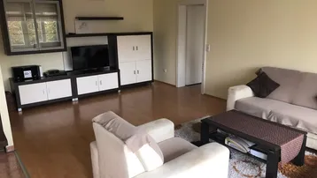 Gemütliches Wohnzimmer mit hellem Sofa, Couchtisch und Medienmöbeln auf Holzfußboden.