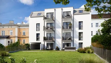 Moderne weiße Wohnanlage mit Balkonen und gepflegter Grünfläche im Vordergrund.