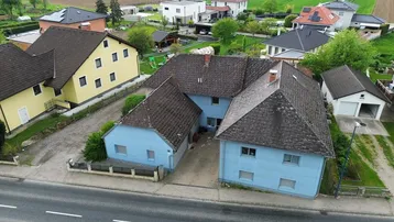 Luftaufnahme eines Wohnhauses mit umliegenden Gebäuden und ländlicher Umgebung.