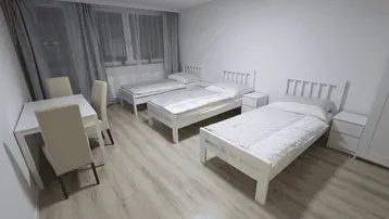 Helles Schlafzimmer mit drei Einzelbetten, Esstisch und Laminatboden, ideal für Gäste.