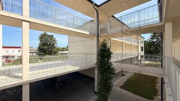 Moderner Innenhof eines Wohngebäudes mit offenen Gängen, Balkonen und Grünflächen.