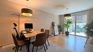 Heller Wohnbereich mit Esstisch, Pflanzen und Zugang zu einem Balkon.