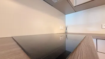 Moderne Einbauküche mit Induktionskochfeld und Dunstabzugshaube in hellem Design.