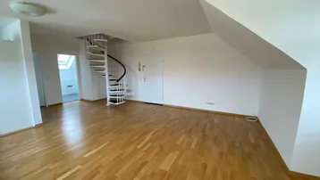 Geräumiger Wohnbereich mit hellem Parkettboden und einer eleganten Wendeltreppe, die in die obere Etage führt.