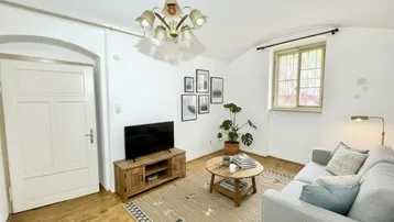 Gemütliches Wohnzimmer mit Holzboden, bequemer Couch und einem Fenster mit Blick ins Grüne.