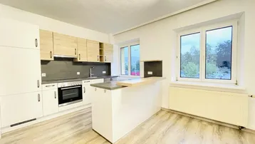 Helle Küche mit modernen Holz- und Weißfronten, einer Kücheninsel und Laminatboden.