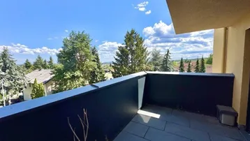 Geräumiger Balkon mit dunklen Fliesen und weitem Blick ins Grüne.