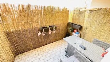 Gemütlicher Balkon mit Rattanmöbeln und Bambus-Sichtschutz, ideal für entspannte Stunden im Freien.