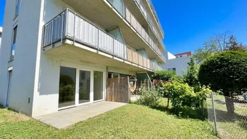 Erdgeschosswohnung mit kleiner Terrasse und direktem Zugang zum grünen Gartenbereich des Gebäudes.