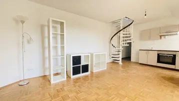 Heller offener Wohnbereich mit Parkettboden, Wendeltreppe und integrierter Küchenzeile.