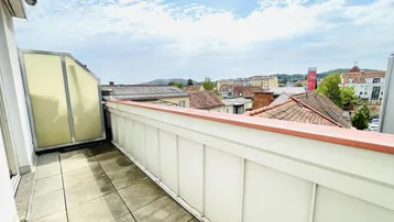 Geräumiger Balkon mit Fliesenboden und weitem Blick über die Dächer der Stadt.