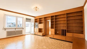 Helles Wohnzimmer mit Parkettboden, großen Fenstern und einer umfangreichen Holzregalwand im Vintage-Stil.
