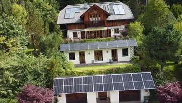 Großzügiges Anwesen mit Haupthaus, Garage und Photovoltaikanlagen, umgeben von viel Grün.
