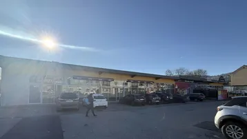 Außenansicht eines modernen Geschäftsgebäudes mit großzügigem Parkplatz unter strahlendem Sonnenschein.