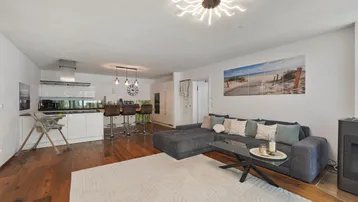 Offener Wohnbereich mit integrierter Küche, großem Sofa und modernem Essbereich.