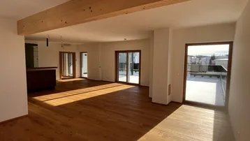 Helles, offenes Wohnzimmer mit Holzbalken, Eichenparkett und Zugang zur Terrasse.