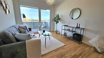 Helles Wohnzimmer mit Holzboden, modernem Sofa und Zugang zum Balkon, ideal für Entspannung.