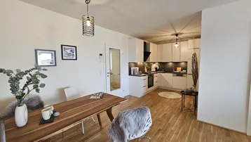 Moderne offene Küche mit weißen Schränken, Holzboden und integriertem Essbereich.