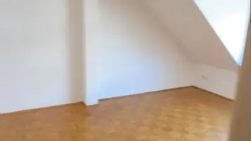 Heller Raum mit Dachschräge und Parkettboden, ideal für Wohn- oder Schlafbereich.