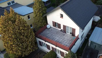Luftaufnahme eines Hauses mit großer Dachterrasse und umliegenden Gebäuden.