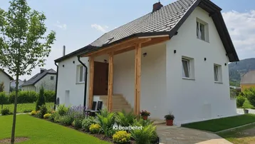 Eingangsbereich des Hauses mit überdachter Holzveranda, Treppe und gepflegtem Rasen.
