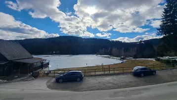 Malerischer Blick auf einen zugefrorenen See umgeben von Wäldern und Bergen.