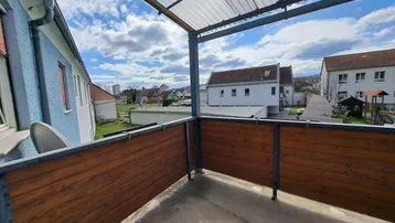 Überdachter Balkon mit Holzverkleidung und Blick auf die umliegende Wohngegend.