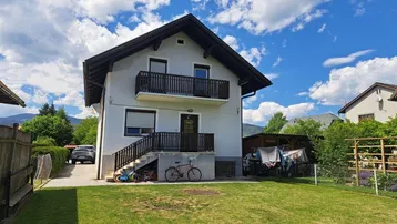 Freistehendes Haus mit Satteldach, Balkonen und einem gepflegten Rasen im Vorgarten.