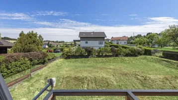 Weitläufiger Blick über eine große Grünfläche, umliegende Häuser und die Landschaft.