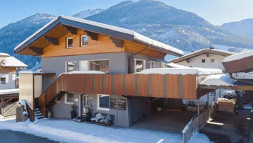 Modernes Gebäude in alpiner Umgebung mit Holzelementen und verschneiter Landschaft.