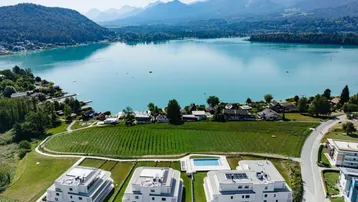Luftaufnahme einer modernen Wohnanlage mit See- und Bergblick, umgeben von Weinbergen und einem Pool.