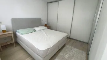 Helles Schlafzimmer mit Doppelbett, Einbauschrank und hellem Holzfußboden.