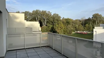 Dachterrasse mit grauen Fliesen, moderner Brüstung und Blick ins Grüne.