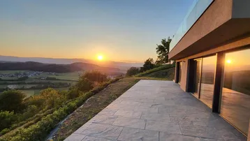 Große Terrasse mit Steinplatten und weitem Blick über die Landschaft bei Sonnenuntergang.