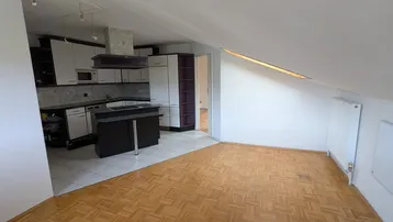 Offene Küche mit weißen und dunklen Schränken, Kochinsel und Fliesenboden im Dachgeschoss.