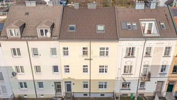 Luftaufnahme von mehreren Reihenhäusern mit unterschiedlichen Fassaden und Dächern in einer Wohngegend.