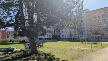 Grüne Außenanlage mit Spielplatz und Mehrfamilienhäusern im Hintergrund, ideal für Familien.