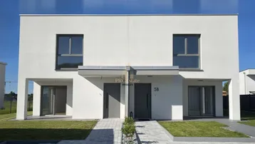 Moderne Doppelhaushälfte mit weißer Fassade, großen Fenstern und gepflegtem Vorgarten.