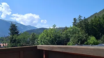 Panoramablick von einem Balkon auf grüne Berge und einen klaren blauen Himmel an einem sonnigen Tag.