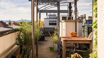 Gemütlicher Essbereich auf der Dachterrasse mit Holzboden und üppiger Bepflanzung.