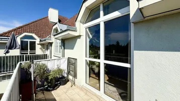 Heller Balkon mit Fliesenboden und Pflanzen, bietet einen schönen Ausblick auf die Umgebung.