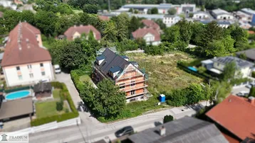 Luftaufnahme eines im Bau befindlichen Gebäudes mit Gerüst und umliegender grüner Landschaft.