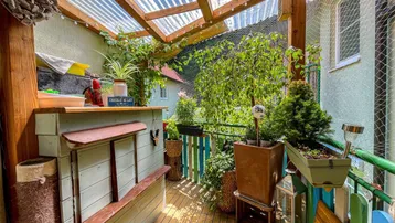 Überdachter Balkon mit Holzboden, Pflanzen und einer kleinen Bar.