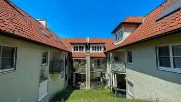Innenhof zwischen Wohngebäuden mit begrünten Flächen und Balkonen.