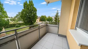 Heller Balkon mit Fliesenboden und Blick ins Grüne, ideal zum Entspannen im Freien.