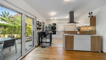 Helle offene Wohnküche mit Holzboden, moderner Ausstattung und direktem Zugang zur Terrasse.