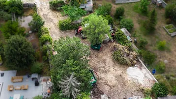 Übersicht aus der Vogelperspektive auf ein unbebautes Grundstück mit Baumbestand und Nachbarhäusern.